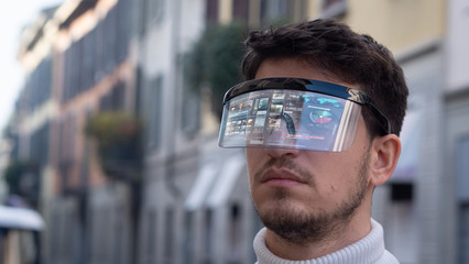 An young man is using futuristic innovative technology vr mask with augmented reality anonymous holograms in a city center. Concept of future,innovation, immersive technology, gaming,virtual reality