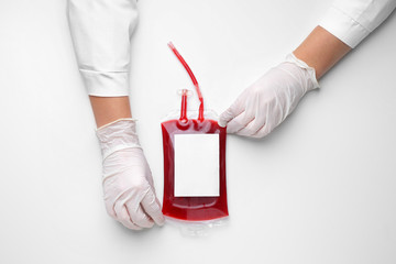 Hands of doctor with blood pack for transfusion on white background - obrazy, fototapety, plakaty