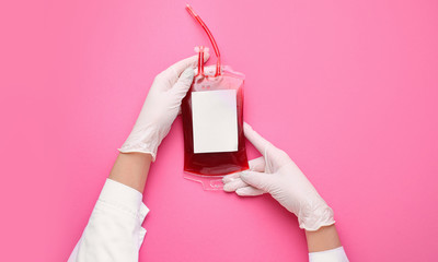 Hands of doctor with blood pack for transfusion on color background