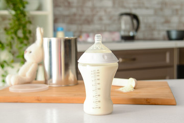 Bottle of baby milk formula on table indoors