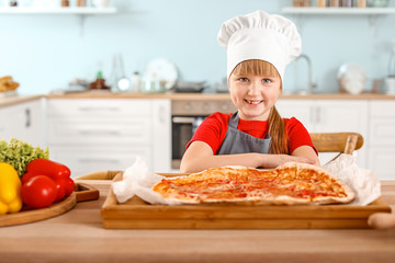 Cute little chef cooking pizza in kitchen