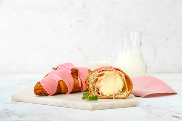 Board with tasty sweet croissants on white background