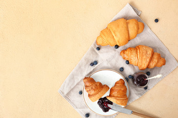 Plate with tasty sweet croissants and jam on color background