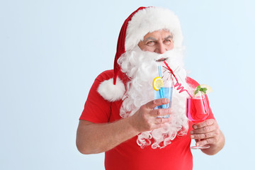 Santa Claus with cocktails on light background. Concept of vacation