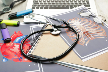 Stethoscope with laptop, drawings of human ribs and heart on table