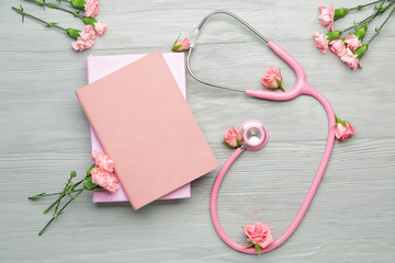 Stethoscope with flowers and notebooks on wooden background