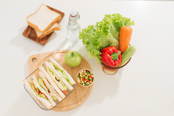 Sandwich with cheese and ham on cutting board on the table in the bright kitchen. Lunch. Sandwich with lettuce. Healthy eating concept.