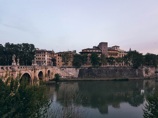 Fototapeta premium Beautiful river scene in Rome with a bridge and houses at early evening. 
