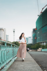 Asian Business Woman traveling, standing by railing bridge, reading book on city background.