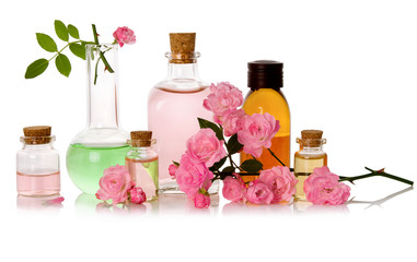 Rose water and essential perfume oil bottled and fresh pink flowers isolated on white background