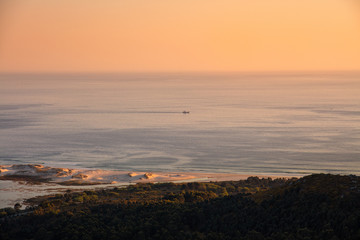 Fototapeta premium Sunset on the Galician coast with a small boat sailing on the sea.