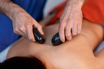 Young Asian woman enjoying the therapeutic effects of a traditional hot stone massage at luxury spa and wellness center