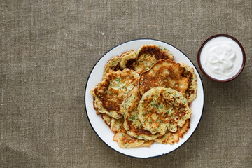 Cheese fritters with greens and sour cream on a textile background