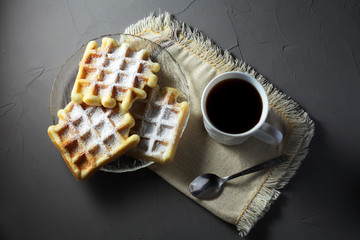 homemade waffles on a transparent plate with a coffee mug on a light table