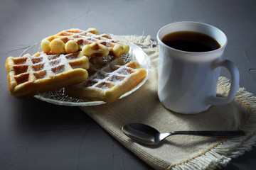 homemade waffles on a transparent plate with a coffee mug on a light table
