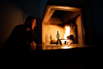 Man sitting in front of a burning fire on a hearth