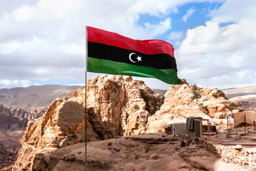 Flag of Islamic republic of Libya waving in mountain background - obrazy, fototapety, plakaty