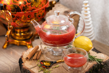Hot fruit red berry tea with steam in the teapot with mint, berries, lemon slices on wooden background. Food and drink. New year holidays, christmas xmas dinner concept