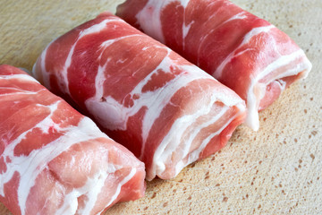 Closeup of three dutch slavinken on a wooden cutting board. Slavink is a dutch meat dish consisting of ground meat wrapped in bacon.