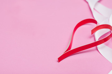 Red paper heart on a pink background with a white ribbon with copy space