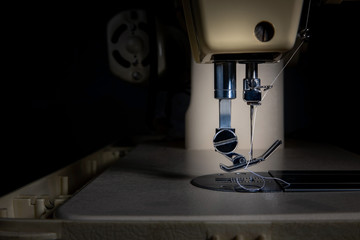 Close-up of a sewing machine on a dark background with backlight, vintage style.