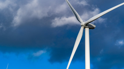 Single wind turbine set against a dark cloudy sky