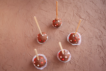 Chocolate candies covered with pink and red hearts on a stick lie
