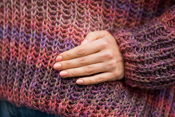 Black-haired woman posing in morning park in a hand-knitted sweater