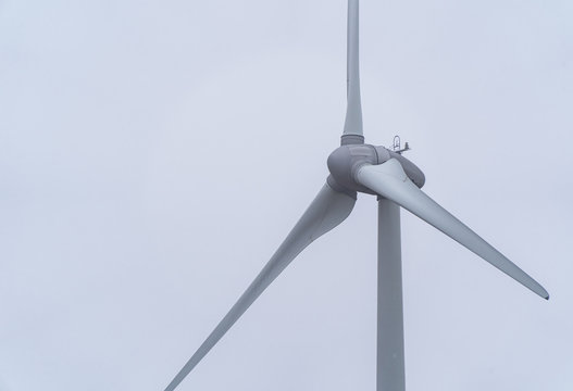 Close Up Of Single Wind Turbine Isolated Against Clear White Sky.