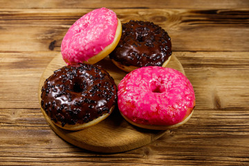 Tasty pink and chocolate donuts on a wooden table