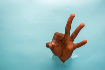 Black man’s Hand showing fingers raised up in between a cardboard