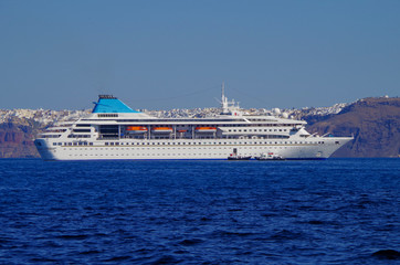 White classic cruiseship or cruise ship liner anchored in bay of volcanic Greek Island of Santorini...