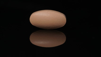 oval tablet isolated on a black background with reflections.
