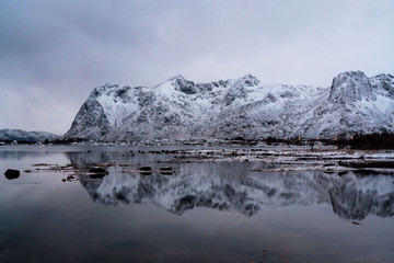 Outstanding snowy mountains reflecting in lake mirror. Winter picture of Lofoten islands, Norway.