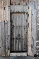 Fototapeta na wymiar old wooden door with rusty tacks of a warehouse or a barn, old gate made of wood, light wooden planks on a rural barn gate, vintage old warehouse wooden gate, wooden texture or background