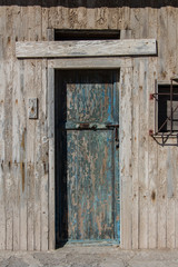 Fototapeta na wymiar old wooden door with traces of blue paint, old wooden door of a warehouse or a barn, old gate made of wood, wooden texture or background, vintage old warehouse wooden gate