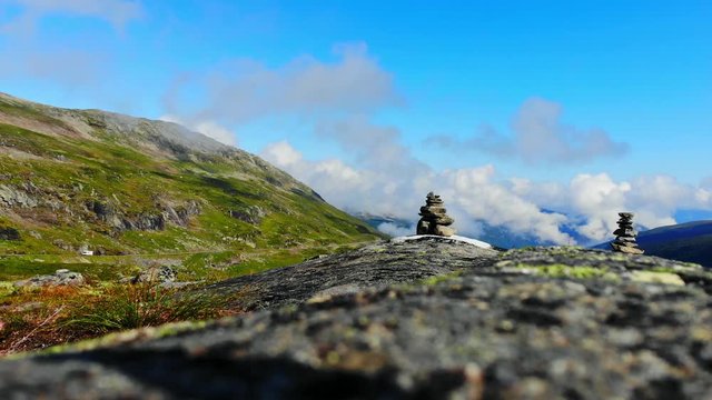 cairn on the aurlandsfjellet mountain and a campervan going up the hill, static shot with amazing skies