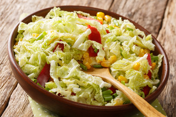 Vitamin organic salad of savoy cabbage with corn, onions and bell pepper close-up in a bowl on the table. horizontal