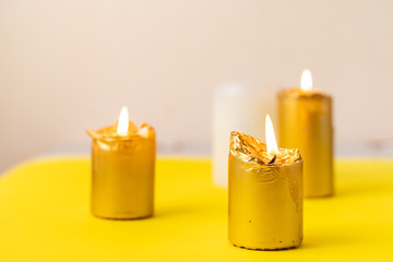 golden candles on yellow background. Wellnes, magic, relax concept. Cozy home. Copy space - obrazy, fototapety, plakaty