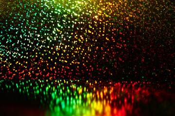 Abstract black background with green, yellow, red shining sparkles shimmer. Disco party backdrop,...