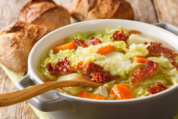 Savoy cabbage soup with potatoes and bacon close-up in a bowl on the table. horizontal