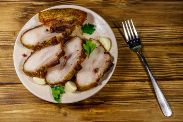 Baked pork belly in a plate on wooden table. Top view