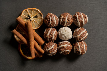 Chocolate balls and cinnamon sticks on dark background.