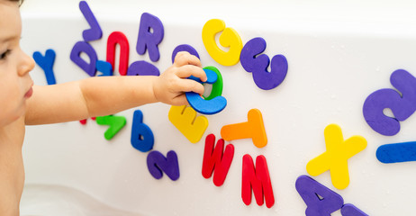 Little girl is playing foam lettern in the bath. Learning abc with play. Montessori activity