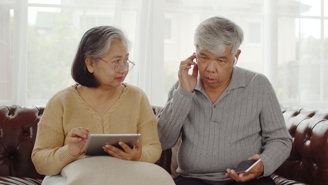 Joyful Senior couple using technology device at home - Powered by Adobe