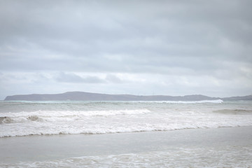 Beach scene with wind turbines on a cliff on an overcast day along the Great Ocean Road at Portland, Victoria Australia