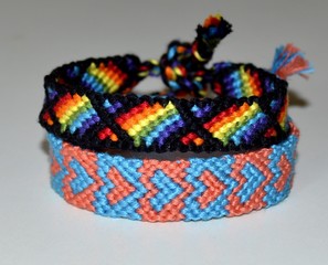 Two woven friendship bracelets with pattern of the rainbow flag (gay pride flag or LGBT pride flag) and hearts