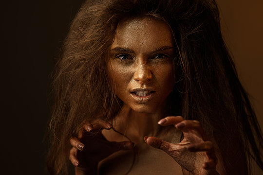 Fashion art portrait of female actress plays the role of a cat, lion or tiger. concept of wild animal inside every woman. beaty woman with gold metallic body and hair on dark background.