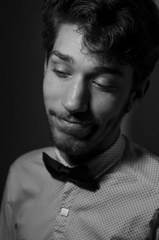 black and white portrait of a cheerful young man with a beard in a white shirt and bow tie. Studio photography