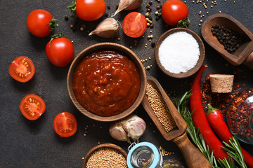 Tomato sauce with spices and chili peppers on a stone table.